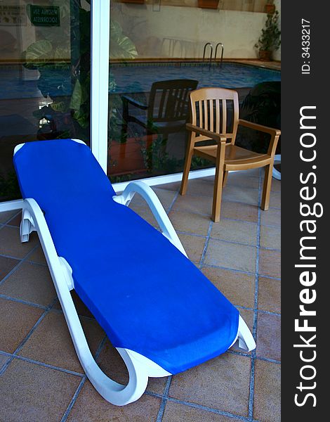 An image of a sun lounger and a chair in a pool.