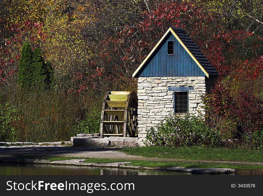 Stone watermill beside a pond during the autumn season.