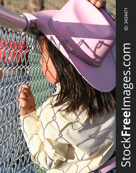 Little cowgirl hanging out by a chain fence. Little cowgirl hanging out by a chain fence