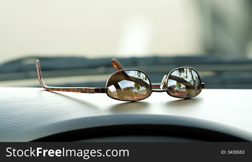 Sunglasses resting on the dashboard of a car. Sunglasses resting on the dashboard of a car