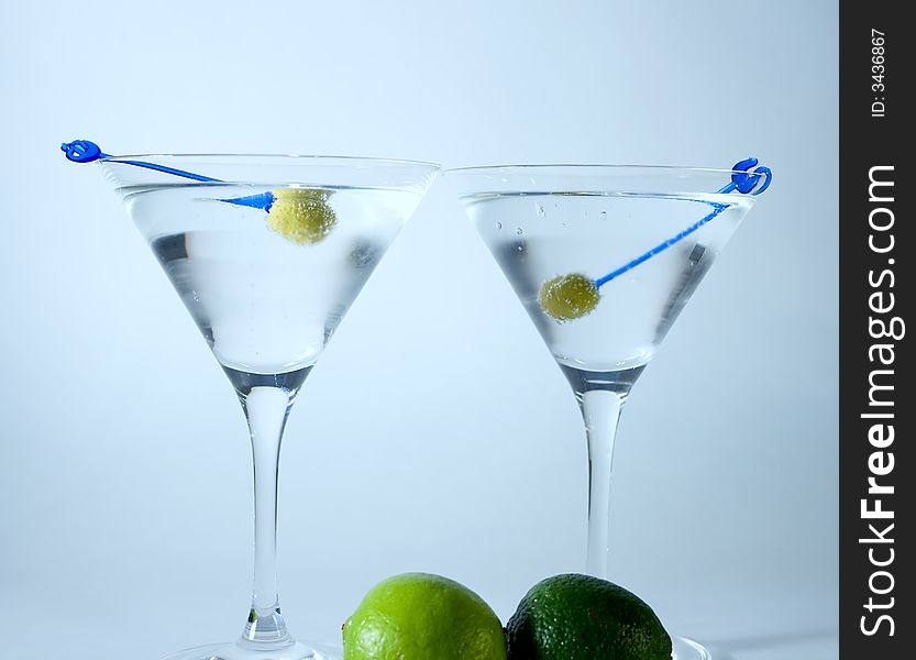 Martini glasses with cocktail and green olives over white background. Martini glasses with cocktail and green olives over white background