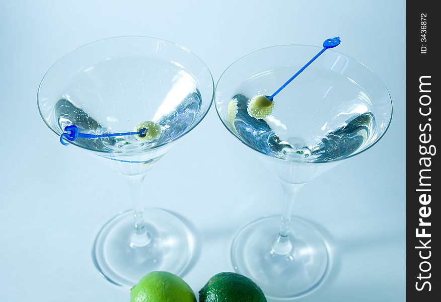 Martini glasses with cocktail and green olives over white background closeup. Martini glasses with cocktail and green olives over white background closeup