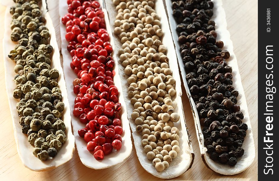 Peppercorns Spices in the sea shells on wood - Black peppercons, Green peppercons, Red peppercons, White  peppercons. Peppercorns Spices in the sea shells on wood - Black peppercons, Green peppercons, Red peppercons, White  peppercons