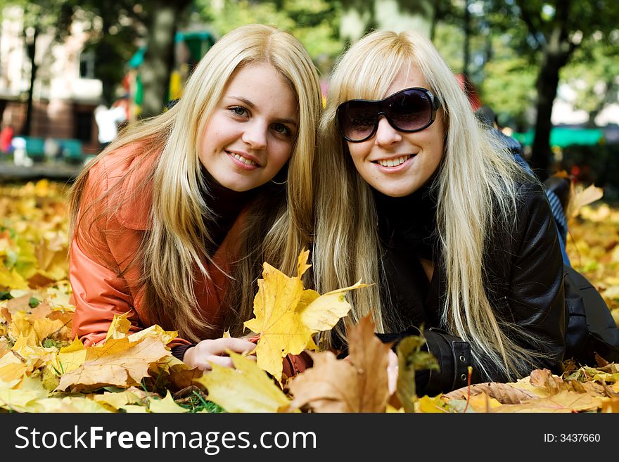 Cute blonde girls on leafs looking and smiling at camera. Cute blonde girls on leafs looking and smiling at camera.