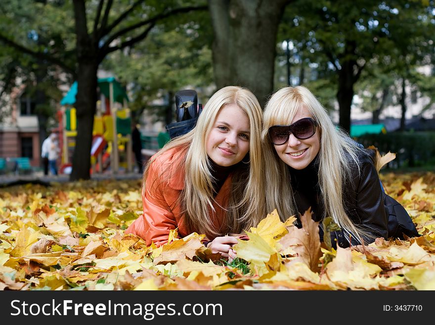 Cute blonde girls on leafs in park. Cute blonde girls on leafs in park.