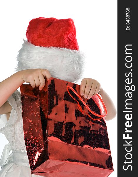 Baby in red santa hat looking in red packege gift over white background