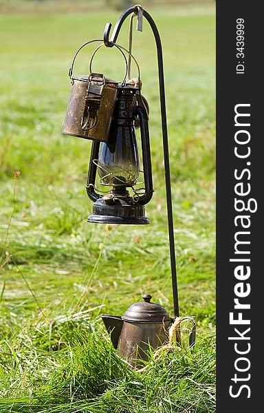 Old lantern and tin teapot hanging on metal post