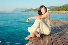Girl Sitting On A Pier Near The Sea Royalty Free Stock Photo