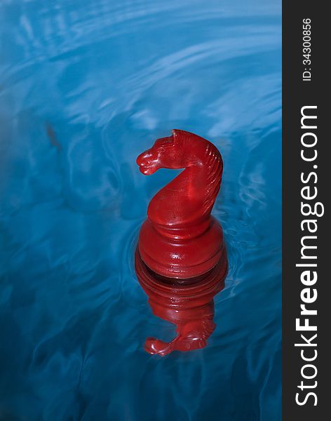 Red chess knight floating on water