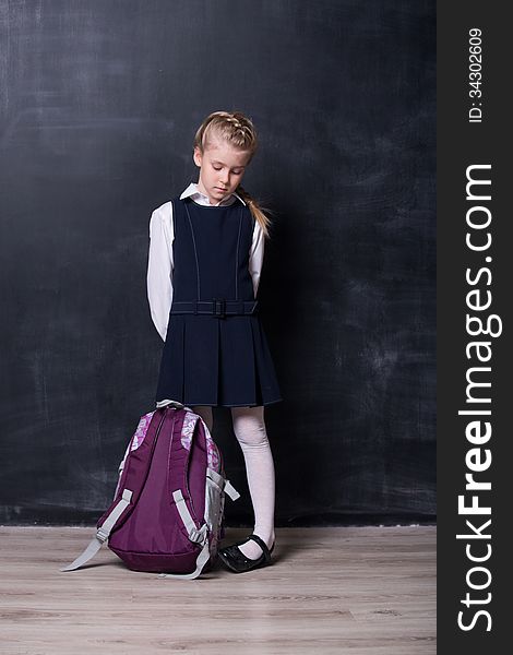 Latecomers little schoolgirl with backpack near blackboard