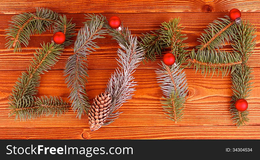 Arrangement of Spruce Branch, Fir Cone and Red Baubles as New Year 2014 closeup on Wooden background