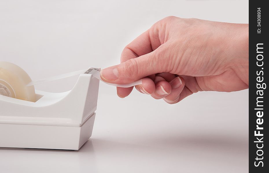 Hand of office worker tearing off tape. Hand of office worker tearing off tape