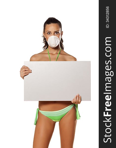 Beautiful brunette with a breathing mask in a bikini holding a blank display. Beautiful brunette with a breathing mask in a bikini holding a blank display