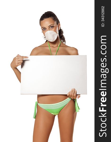 Beautiful brunette with a breathing mask in a bikini holding a blank display and pointing a finger. Beautiful brunette with a breathing mask in a bikini holding a blank display and pointing a finger