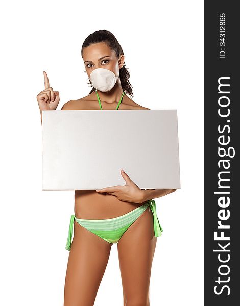 Beautiful brunette with a breathing mask in a bikini holding a blank display and pointing a finger. Beautiful brunette with a breathing mask in a bikini holding a blank display and pointing a finger