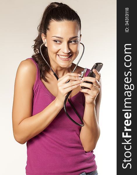 Young beautiful smiling girl uses a stethoscope to tap phones. Young beautiful smiling girl uses a stethoscope to tap phones