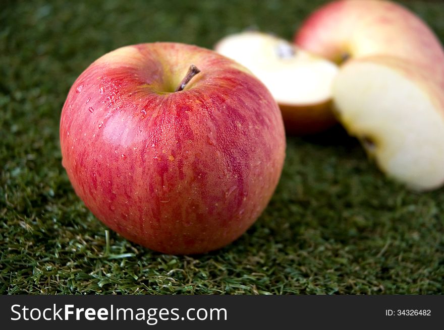 Fresh red apple on green grass with apple slices background