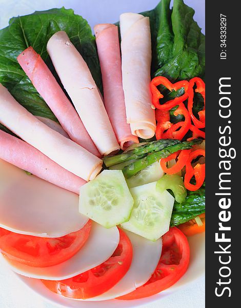 A colorful appetizing plate of assorted raw veggies with cold cuts of turkey, ham and cheese. A colorful appetizing plate of assorted raw veggies with cold cuts of turkey, ham and cheese.