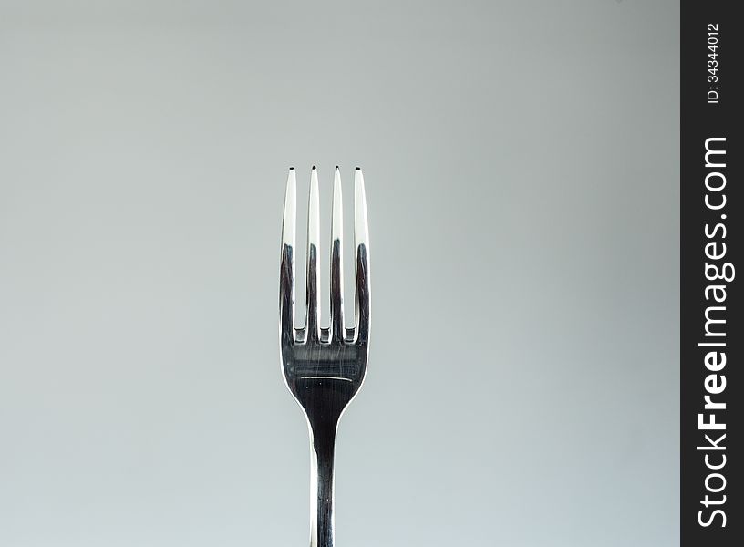 Stainless fork isolated over a light gray background