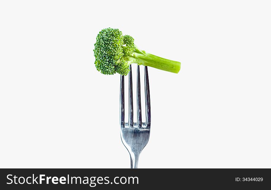 Broccoli on a fork over a gray white background