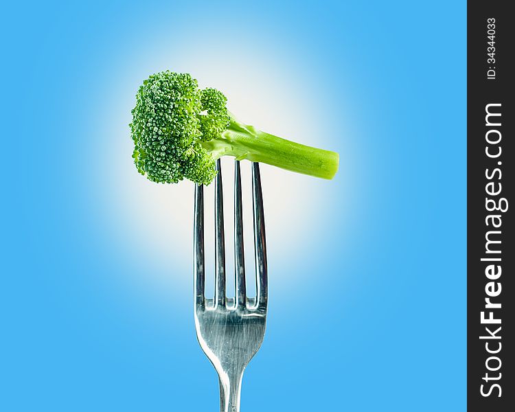 Broccoli on a fork over a blue background. Isolated path on PSD available.
