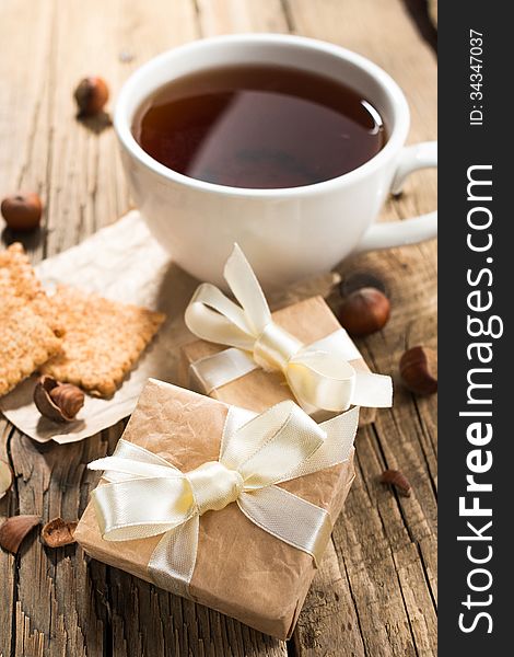 Cup of tea with gift boxes on old wooden background