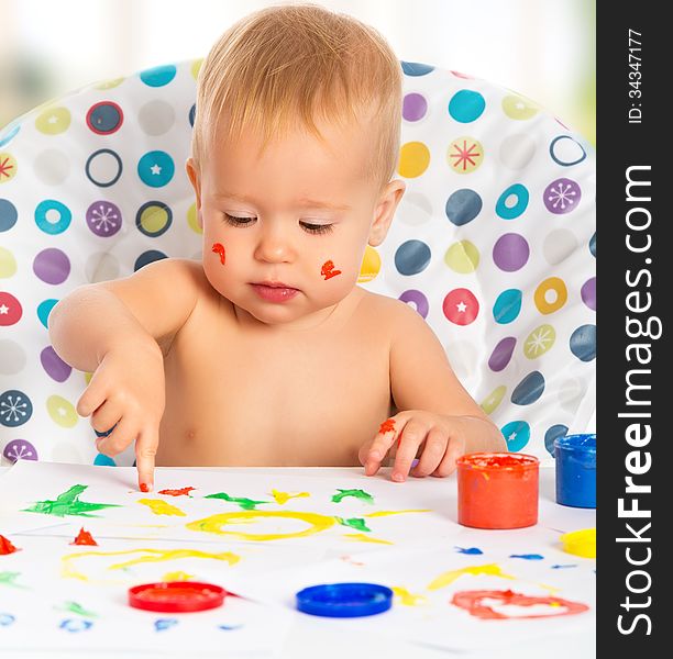 Happy baby child draws with colored paints hands
