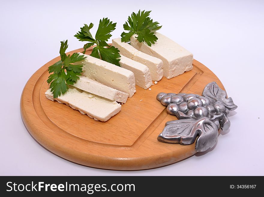 Hard ricotta cheese with celery leaves on kitchen table adorned with a bunch of grapes steel. Hard ricotta cheese with celery leaves on kitchen table adorned with a bunch of grapes steel