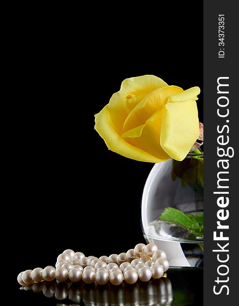 Pearls and yellow rose in a vase on a black background. Pearls and yellow rose in a vase on a black background