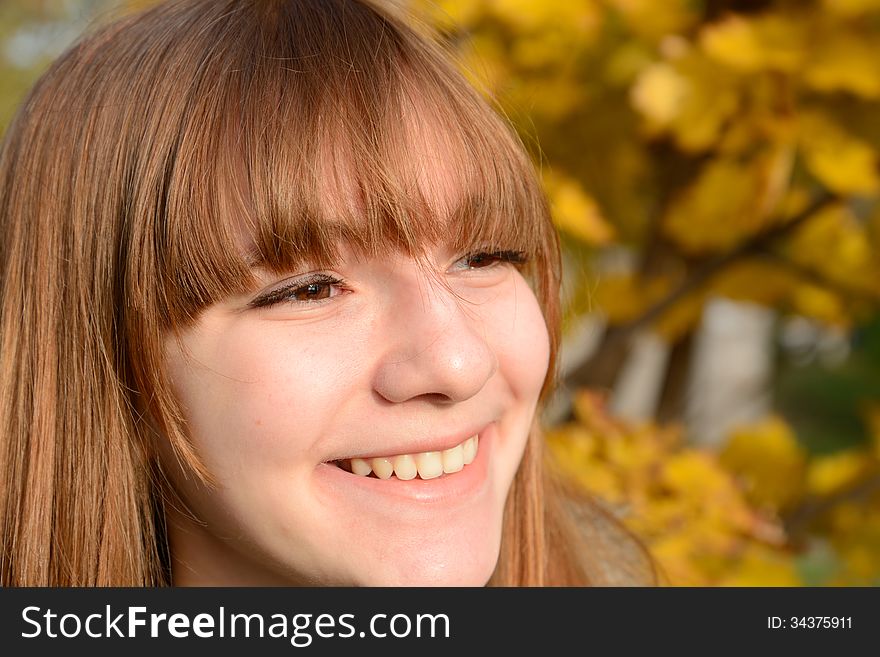 Beautiful young girl with red hair, against the backdrop of golden autumn