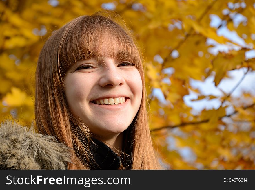 Beautiful young girl with red hair, against the backdrop of golden autumn