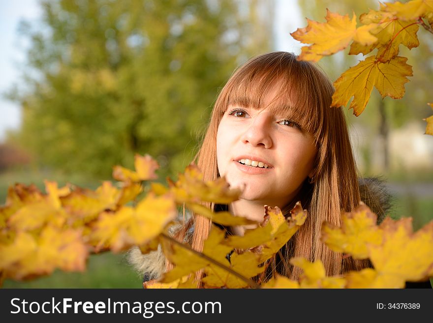 Beautiful young girl with red hair, against the backdrop of golden autumn