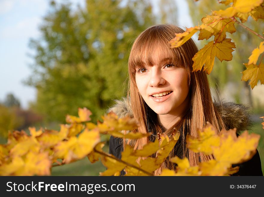 Beautiful young girl with red hair, against the backdrop of golden autumn