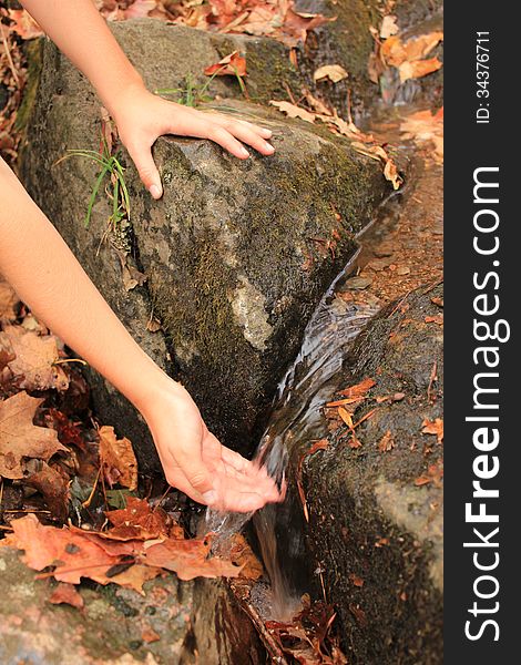 A kid's hand touching a mountain water stream. A kid's hand touching a mountain water stream