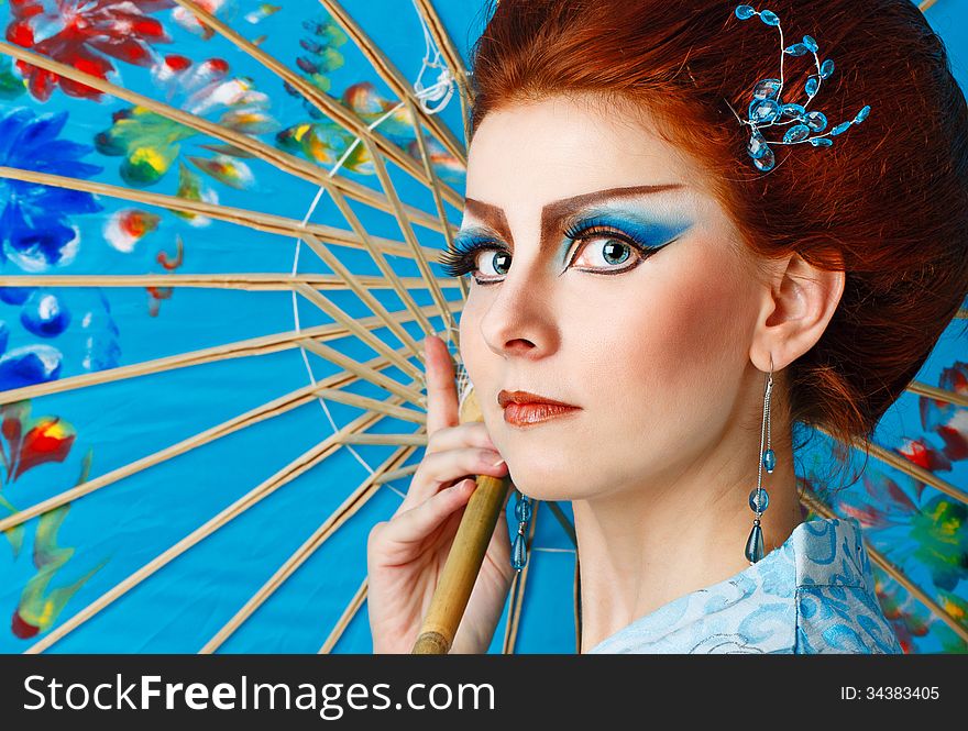 Attractive geisha in a smart dress with an umbrella, photographed in the studio. Attractive geisha in a smart dress with an umbrella, photographed in the studio