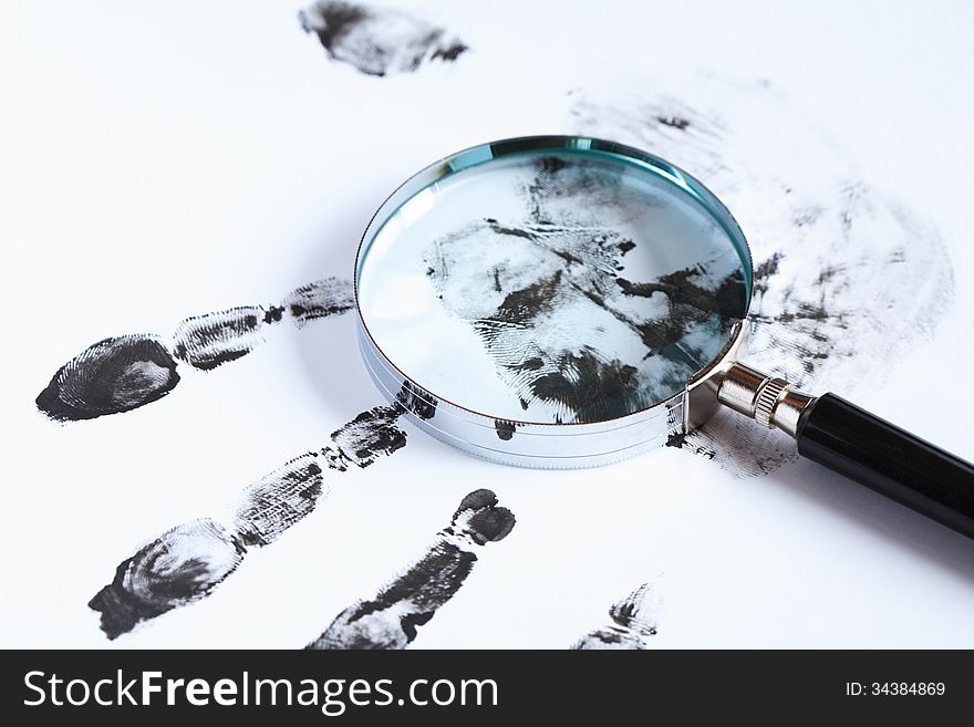 Crime concept. Black fingerprints and magnifying glass on white background