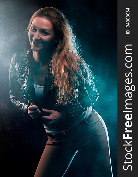 Portrait of amazing young woman with curly blond hair dressed in stylish black jacket. Over blue color spotlight. Portrait of amazing young woman with curly blond hair dressed in stylish black jacket. Over blue color spotlight.