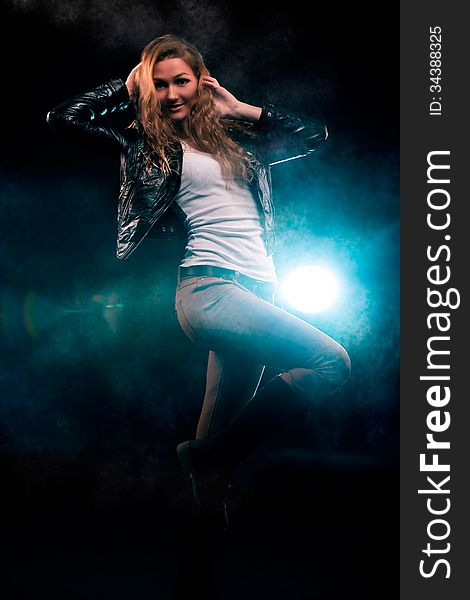 Portrait of amazing young woman with curly blond hair dressed in stylish black jacket. Over blue color spotlight. Portrait of amazing young woman with curly blond hair dressed in stylish black jacket. Over blue color spotlight.