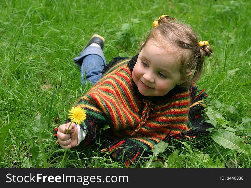 Little girl on grass try to pick a flower