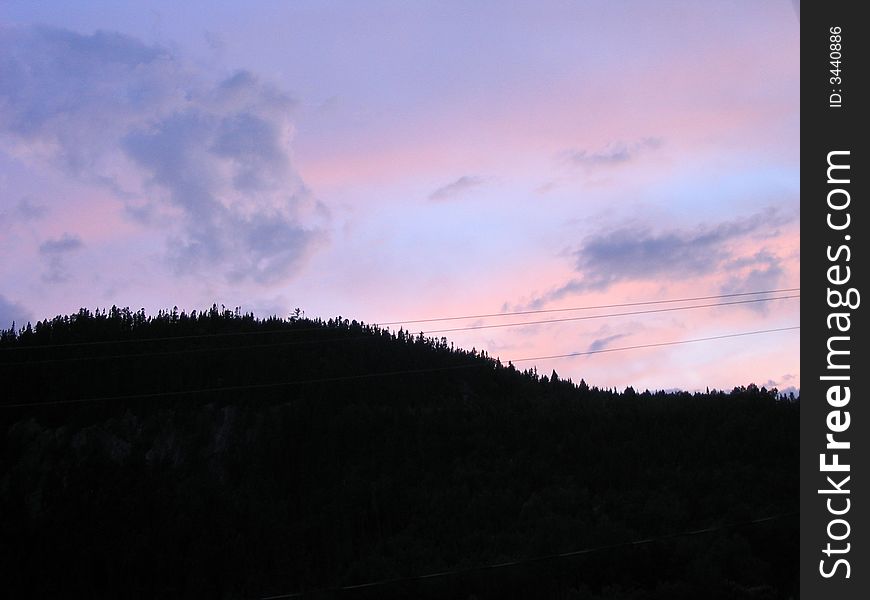Mountain of trees with a purple and blue sky during the summer with electric line. Mountain of trees with a purple and blue sky during the summer with electric line