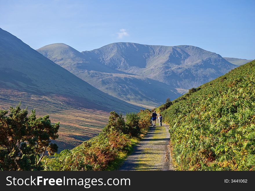 A Father & daughter hiking in Coledale in the English Lake District with Eel crag beyond. They are accompanied by a small dog