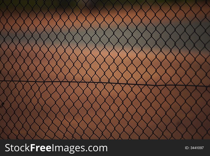 Tennis court fence, focus on the fence and court blurred