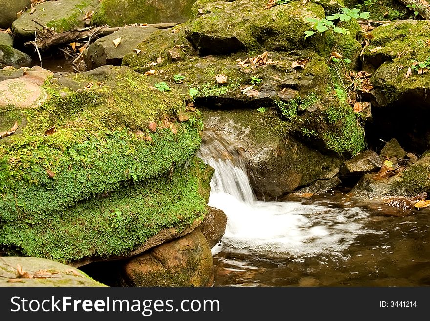 Small waterfall and mossy rocks in forest. Small waterfall and mossy rocks in forest