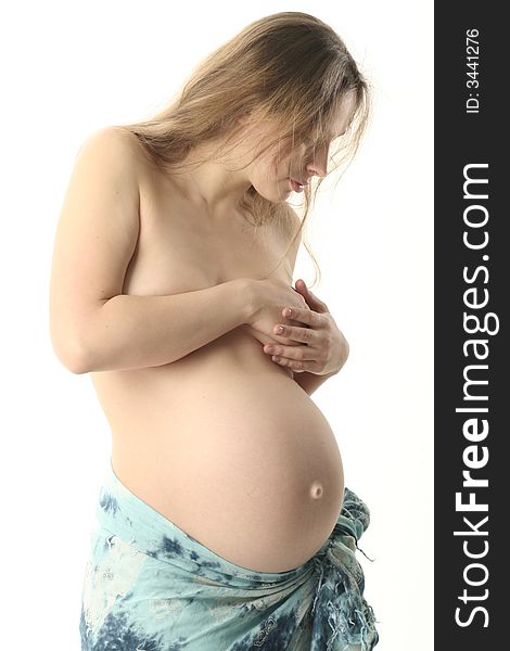 Beautiful belly in skirt from pale blue shawl stand sideview to a viewer. She look on her belly and thinking about baby.