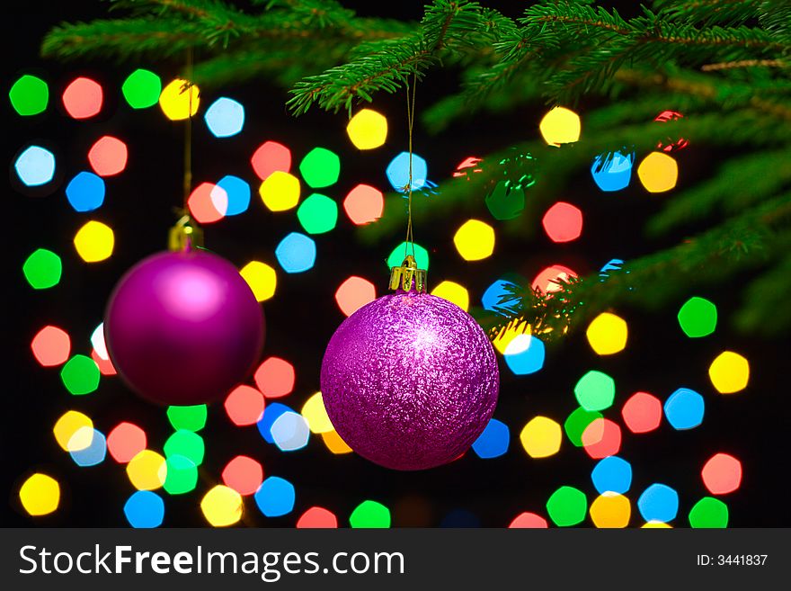 Christmas spheres hang on a fur-tree on a background of a color garland