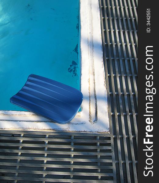 Blue kick board sitting on corner of the pool