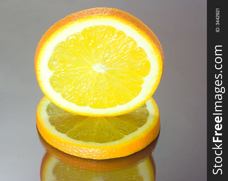 Two orange slices on mirror table, one over another. Two orange slices on mirror table, one over another