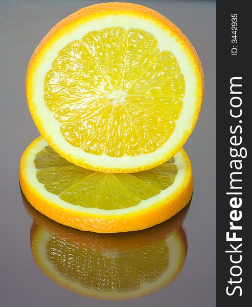 Two orange slices on mirror table, one over another. Two orange slices on mirror table, one over another