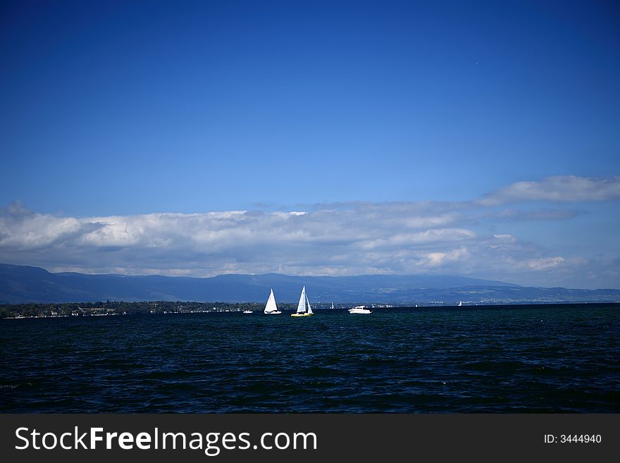 The sailboat at the far end of the picture and the blue sky and white clouds forms a beautiful picture. The sailboat at the far end of the picture and the blue sky and white clouds forms a beautiful picture.