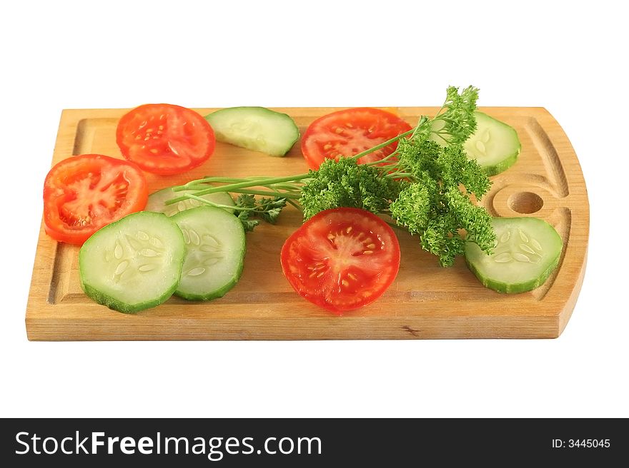 Tomatoes, cucumbers and parsley on a board isolated on white. Tomatoes, cucumbers and parsley on a board isolated on white.